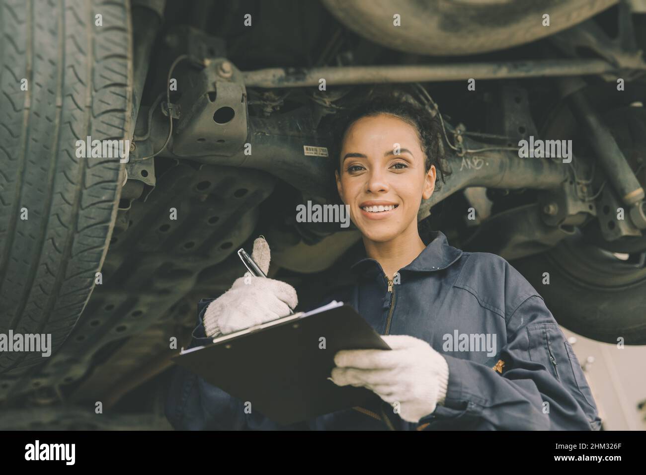 good condition car undercarriage check concept, woman mechanic worker work checklist car garage. Stock Photo