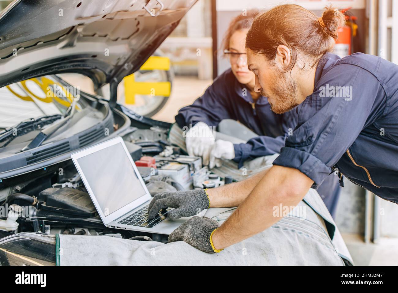 Meachnic staff worker using laptop computer check ane tuning car engine in garage Stock Photo