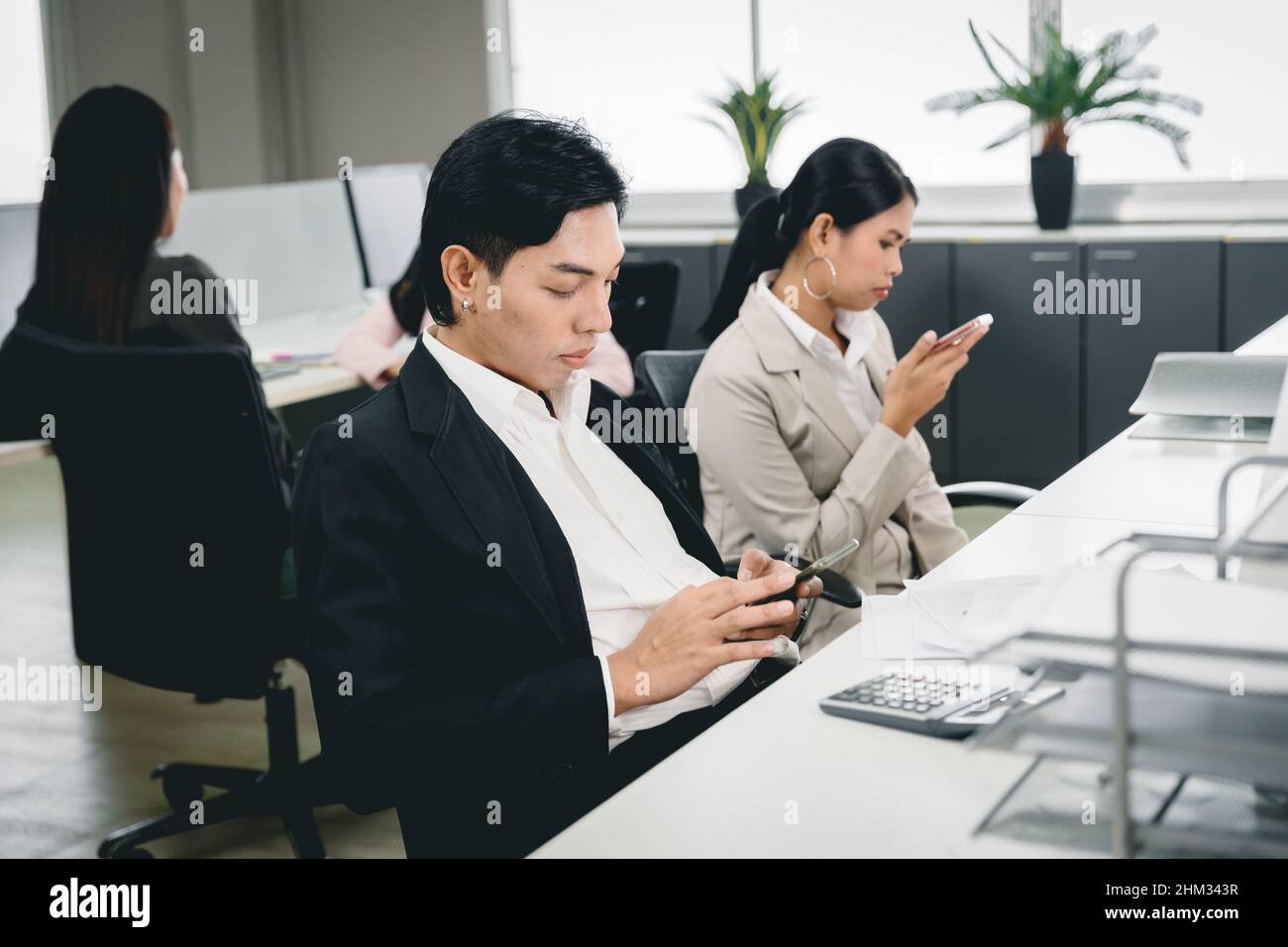 Office employee playing smartphone at work and social media addicted bad habit for business company problem. Stock Photo