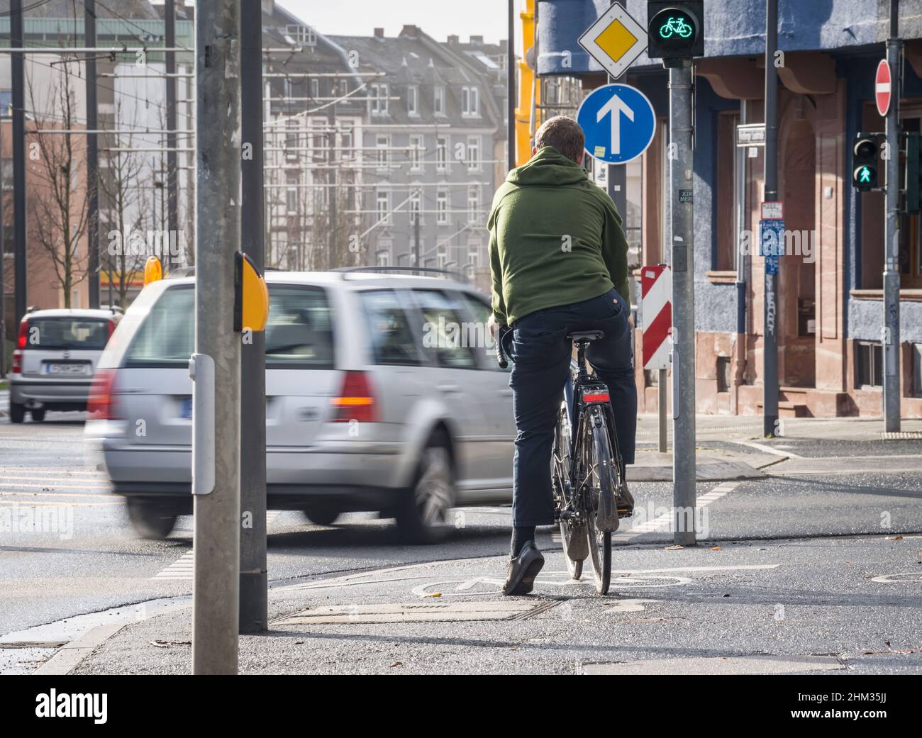 02 February 2022, Hessen, Frankfurt/Main: Ansgar Hegerfeld (29), the deputy chairman of the ADFC Hessen, is riding his bicycle on a bike path on the busy Friedberger Landstraße, while vehicles turn right in front of him. (to dpa: ''Pushed off and insulted' - the everyday fight on the roads') Photo: Frank Rumpenhorst/dpa/Frank Rumpenhorst/dpa Stock Photo