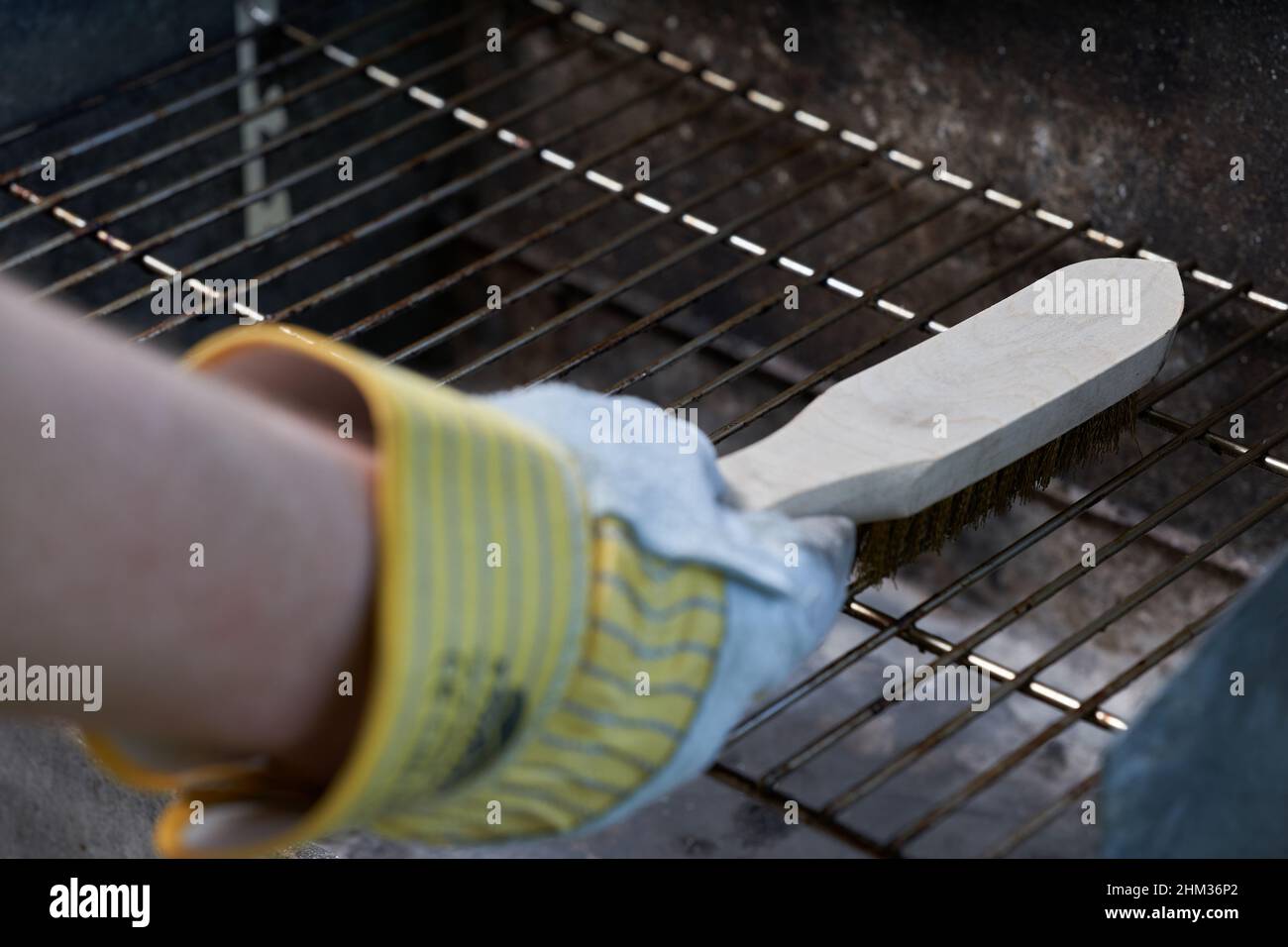 With wire brush clean dirty grill rust. Protect gloves. Stock Photo