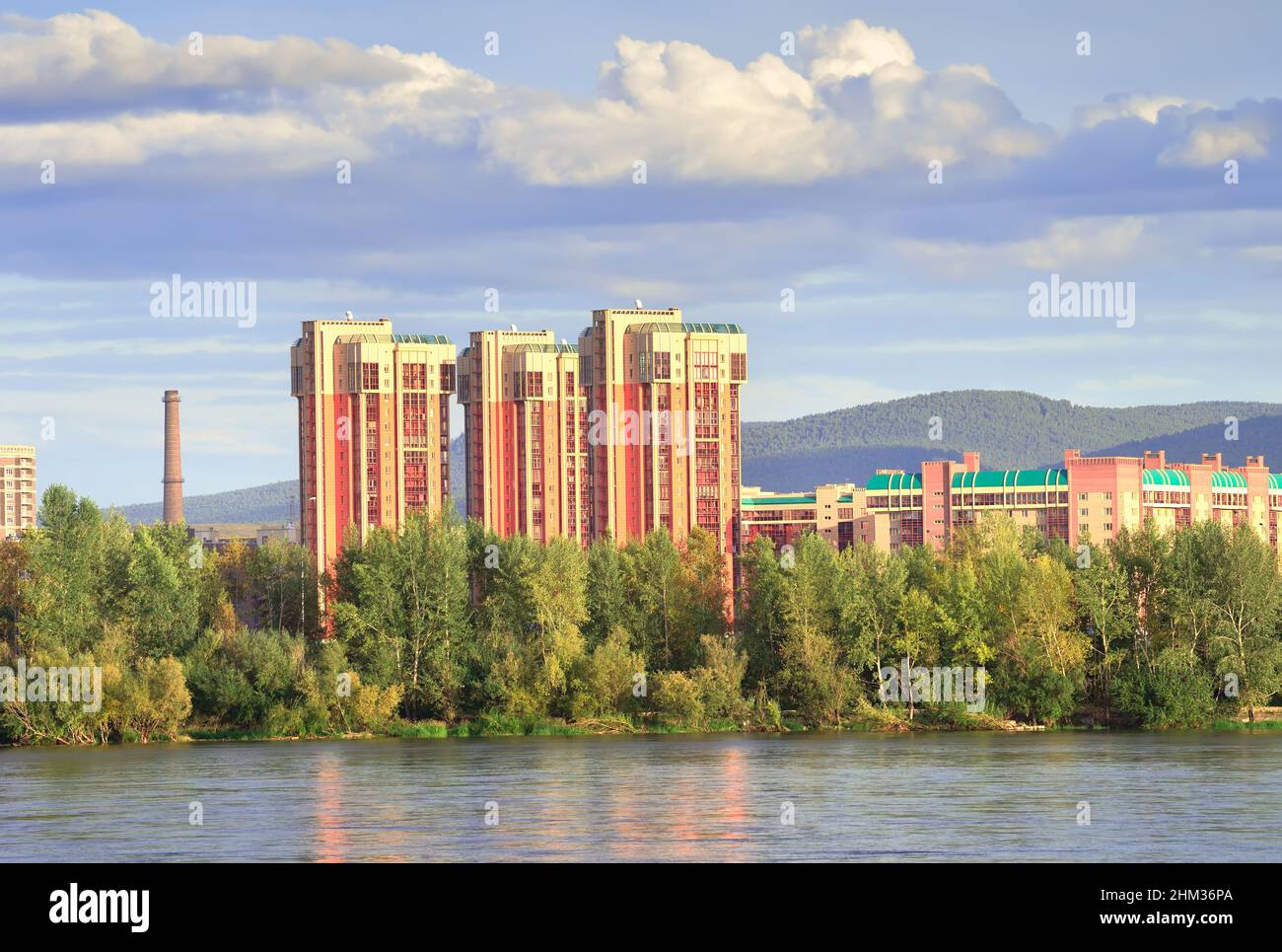 High-rise buildings of the Yuzhny microdistrict against the background of mountains under a blue cloudy sky. Krasnoyarsk, Siberia, Russia Stock Photo