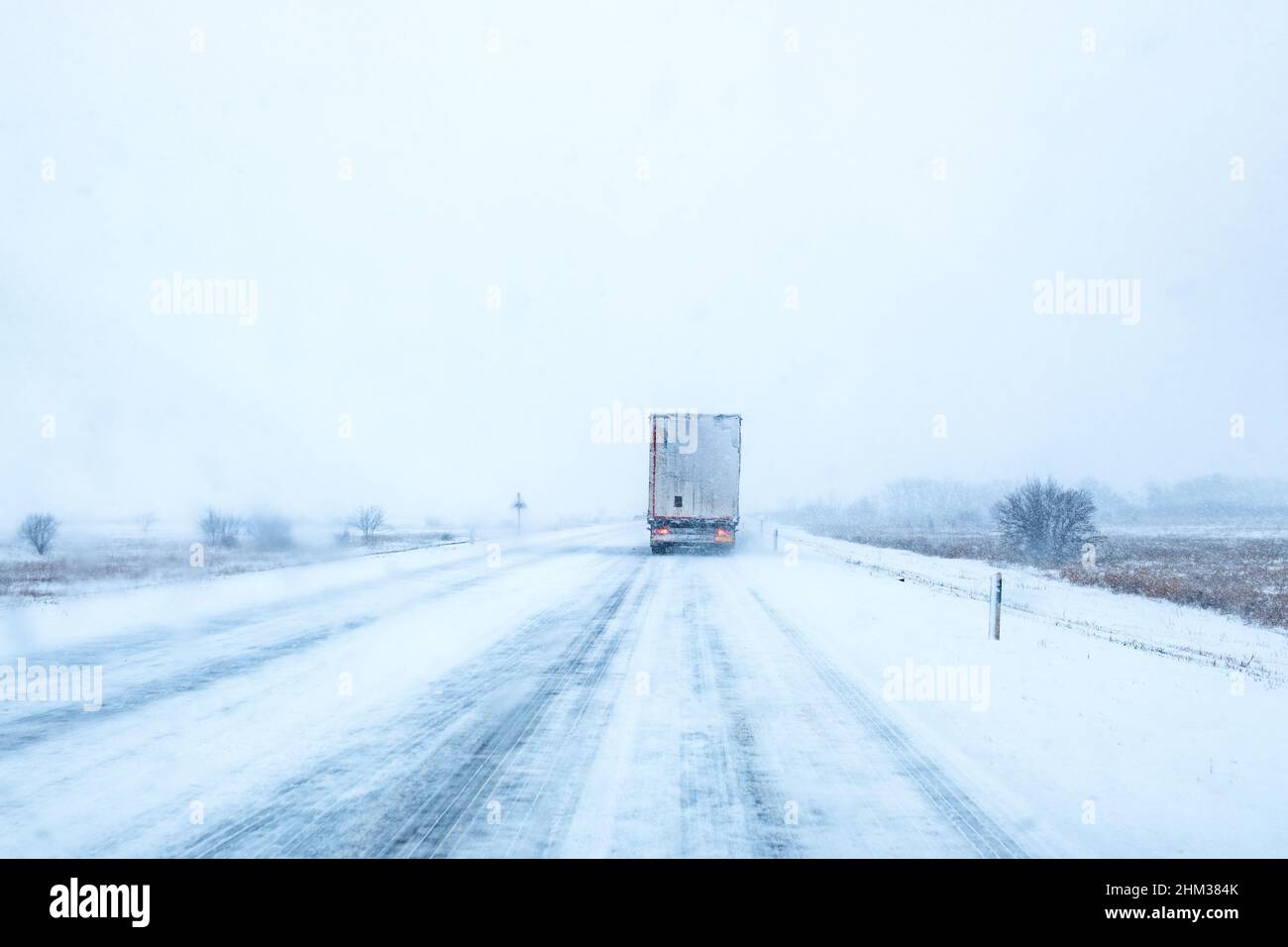 Freight transportation truck on the road in snow storm blizzard, bad weather conditions for transportation event, selective focus Stock Photo