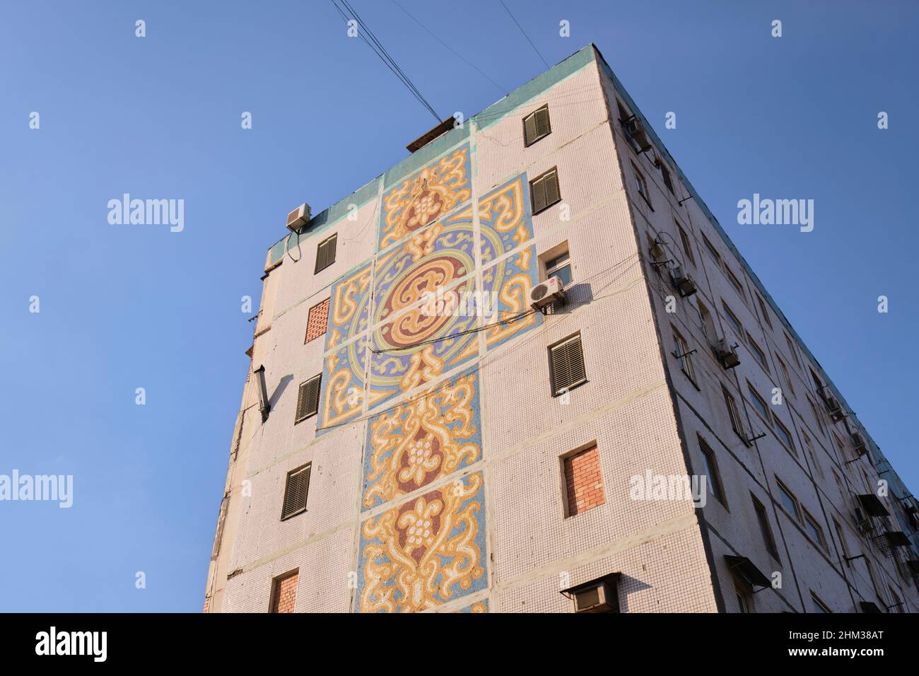 Soviet, Russian, USSR, CCCP era huge art mosaic tile mural shaped like a cross on the end of a large apartment building. In Tashkent, Uzbekistan. Stock Photo
