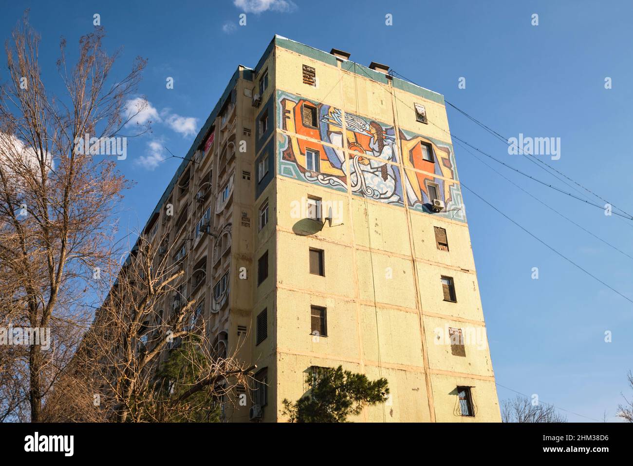 Soviet, Russian, USSR, CCCP era huge art mosaic tile mural on the end of a large apartment building, depicting a woman with water bounty. In Tashkent, Stock Photo