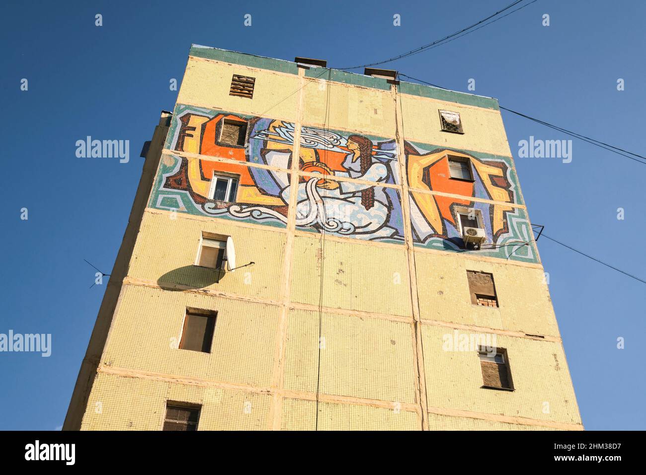 Soviet, Russian, USSR, CCCP era huge art mosaic tile mural on the end of a large apartment building, depicting a woman with water bounty. In Tashkent, Stock Photo