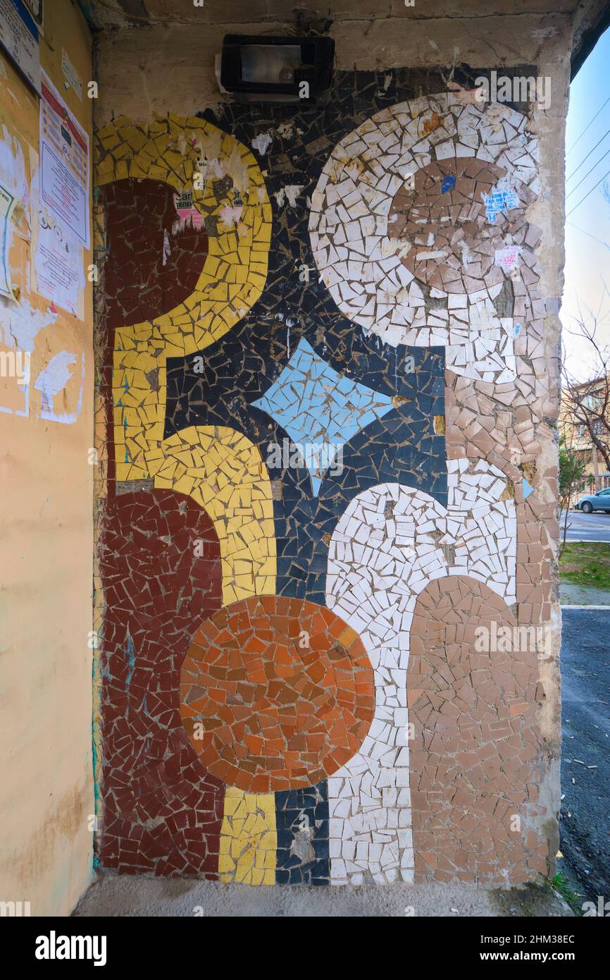 Colorful detail of a Soviet, Russian, USSR, CCCP era art mosaic tile mural at the exterior entrance doorway of a large apartment building. In Tashkent Stock Photo