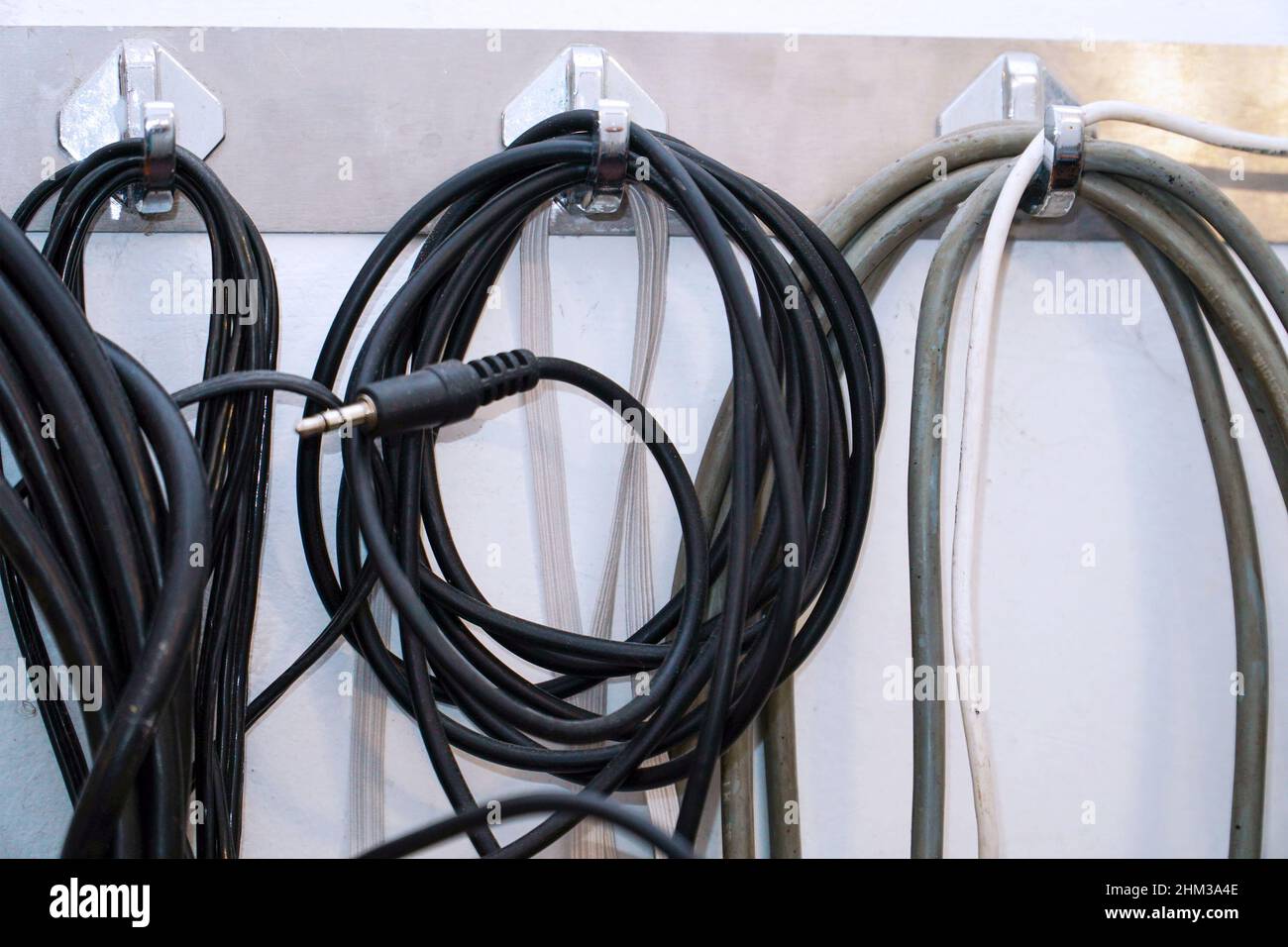 Coiled audio cables hang on the wall in the studio Stock Photo