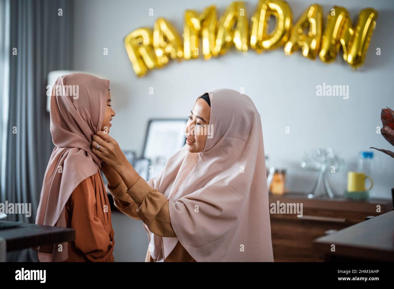 muslim mother fixing her dauhgter headscarf on ramadan Stock Photo