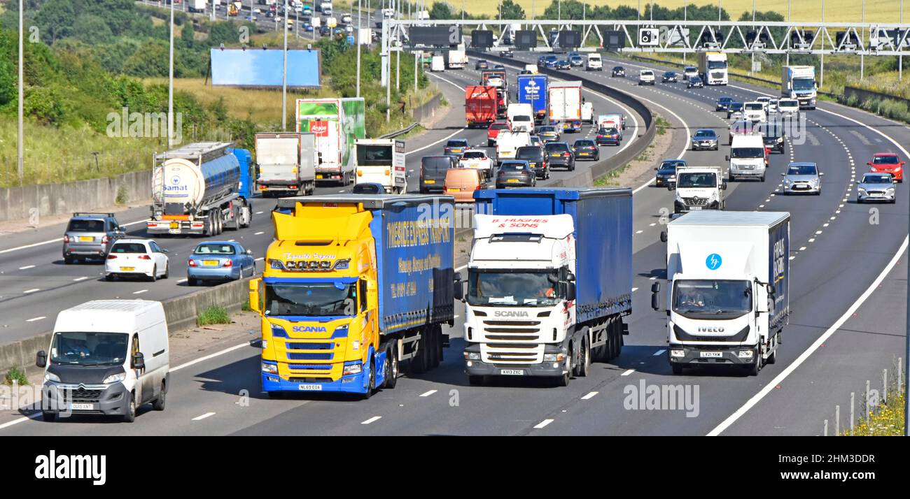 Transport lorry truck four lanes of M25 motorway Essex countryside white van overtakes slower hgv lorries & trucks busy traffic on gradient England UK Stock Photo