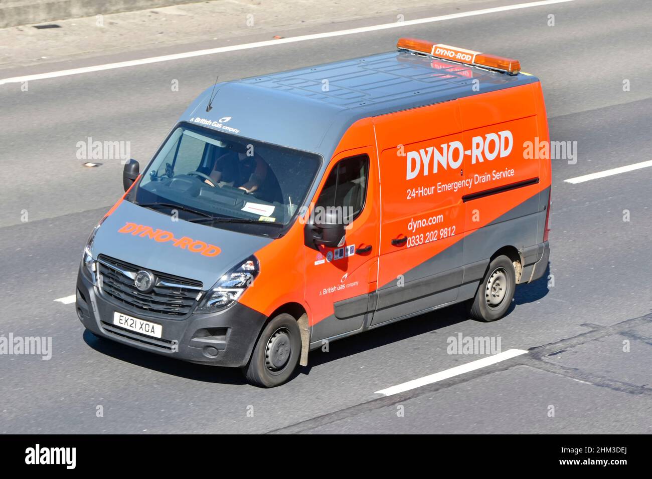 Side aerial view of Dyno Rod van & driver a British Gas company business advertising 24 hour emergency Drain service in vehicle driving 0n uk motorway Stock Photo