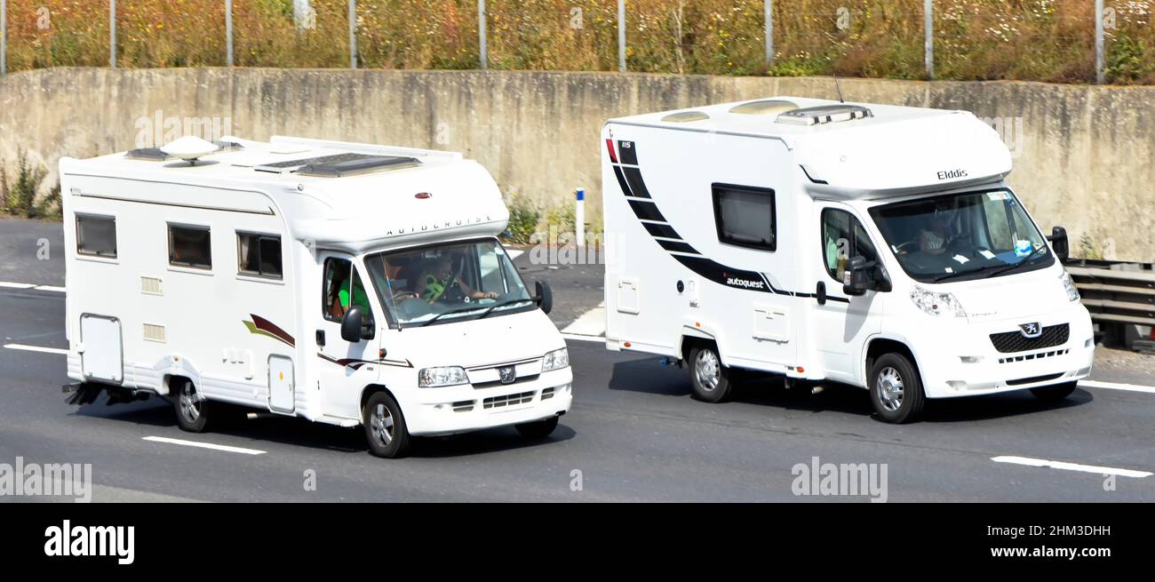 White camper van overtaking Eldiss Autoquest motorhome both  Peugeot side & front view with driver & passenger couples driving along UK motorway road Stock Photo