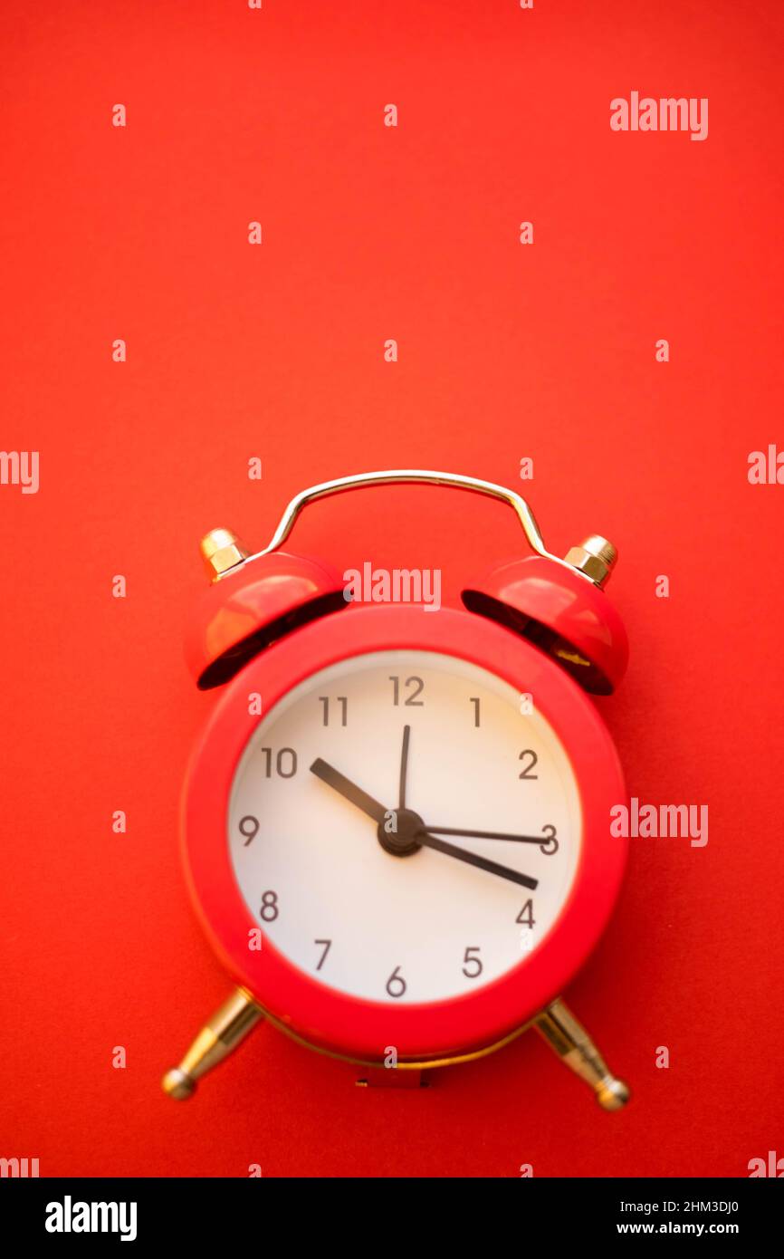 new red round clock on red table, side view. Stock Photo