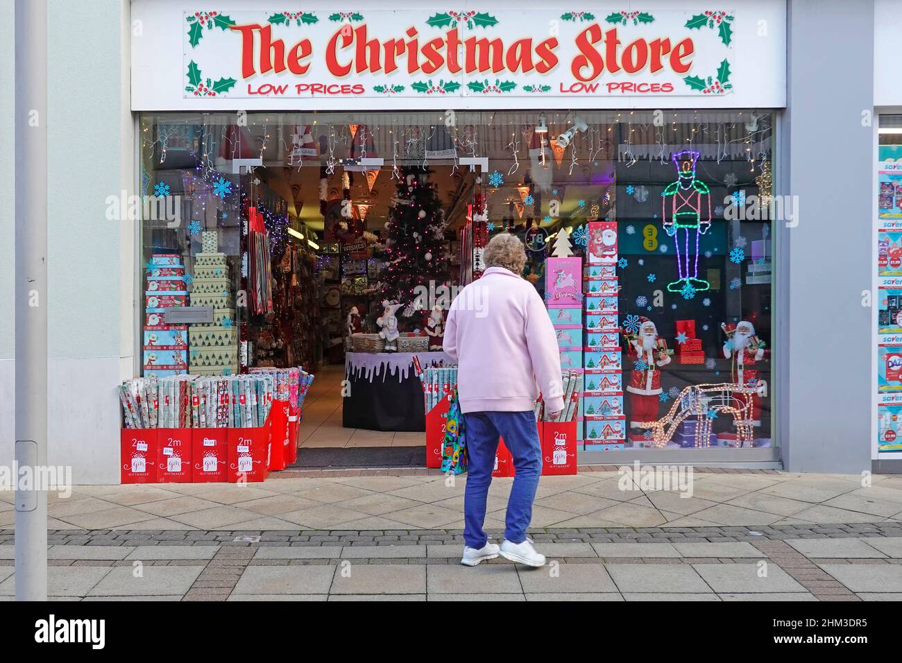 Shopper outside The Christmas Store shop front Xmas merchandise on display in pop up retail business short let premises shopping centre Brentwood UK Stock Photo