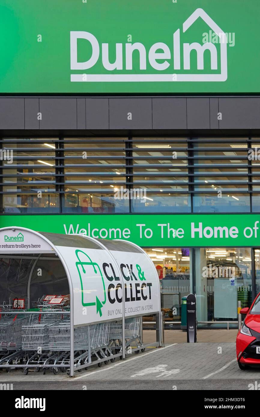 Dunelm welcome store logo home of a Soft furnishing business with click & collect sign on shopping trolley shed in retail car park Essex England UK Stock Photo