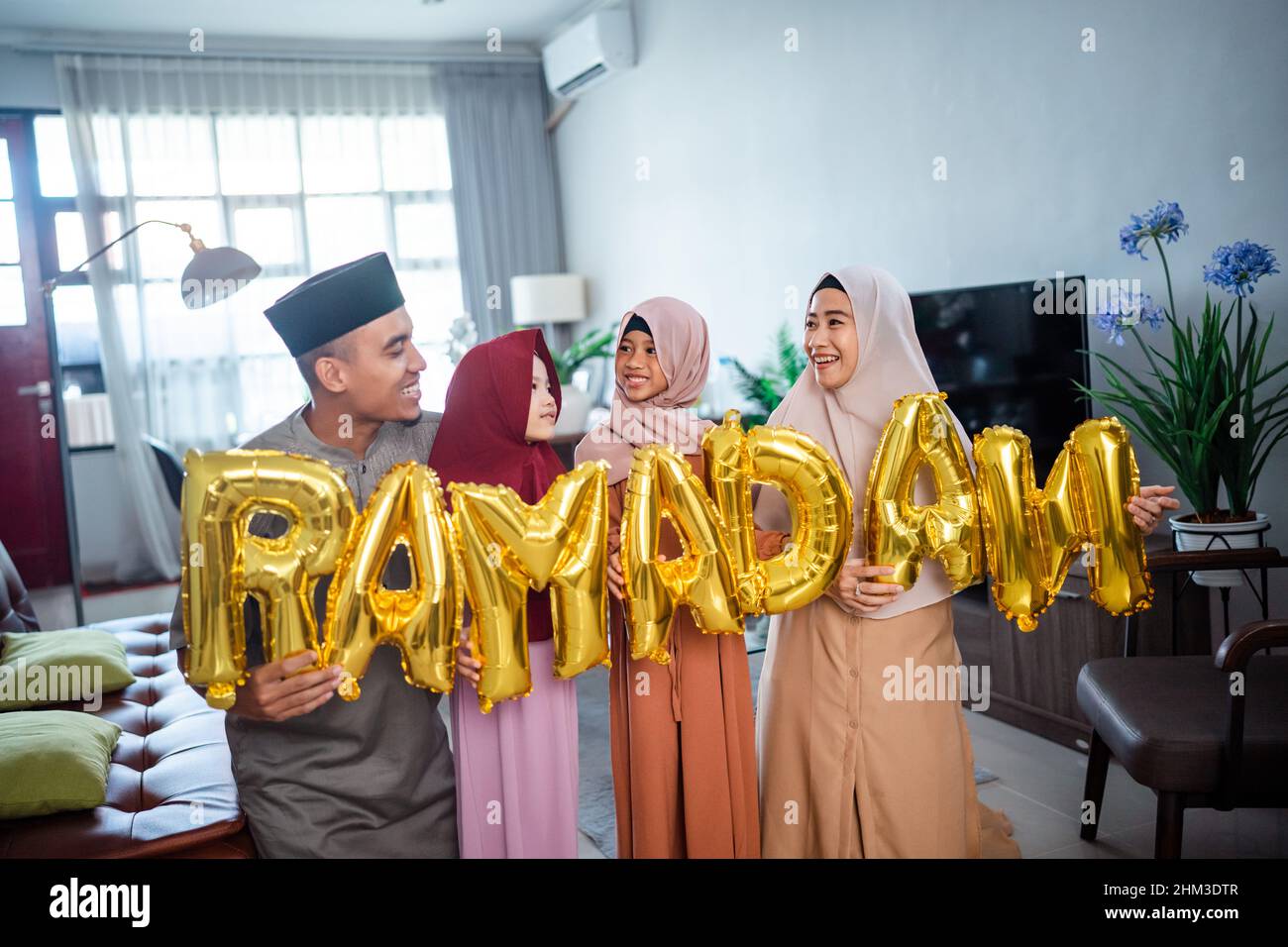 family wearing muslim traditional clothes holding a text of ramadan Stock Photo