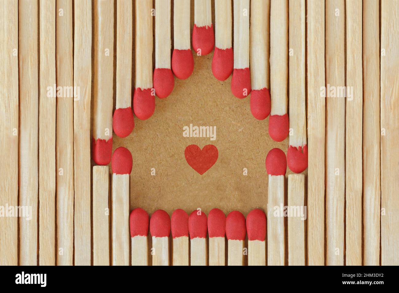 House made of matches with heart on recycled paper background Stock Photo