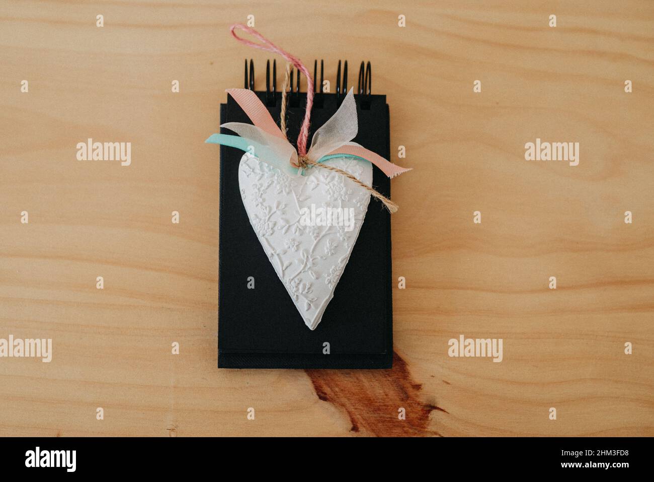 notebook with black sheets with copy space, on a wooden table with a white heart. Stock Photo