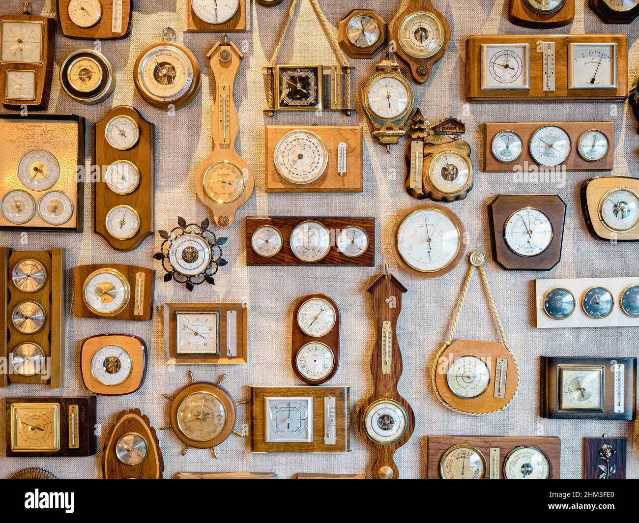 collection of retro old barometers and watches hanging on a textured wall Stock Photo