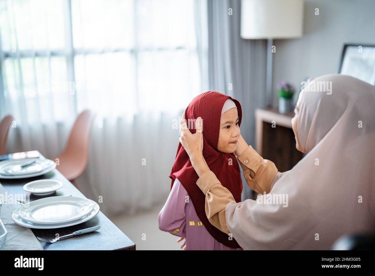 muslim mother fixing her dauhgter headscarf on ramadan Stock Photo