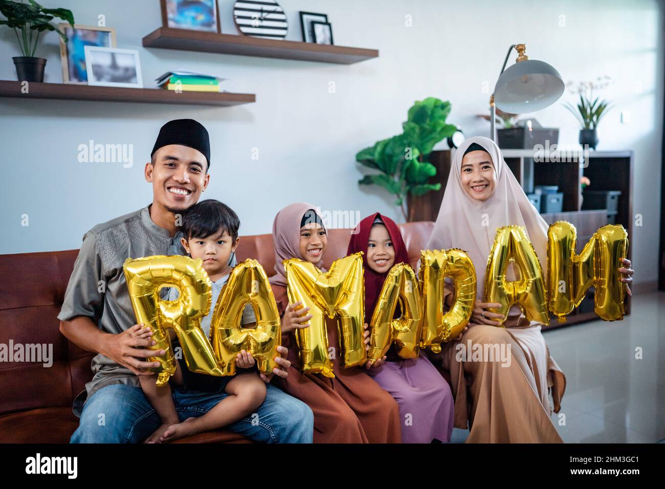 family wearing muslim traditional clothes holding a text of ramadan Stock Photo