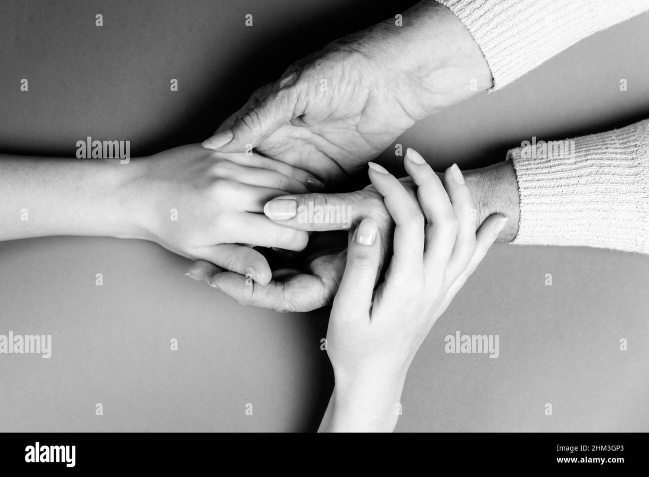 Mother and daughter holding hands. Close-up. Flat lay. Black and white colors. The concept of caring for the elderly. Stock Photo