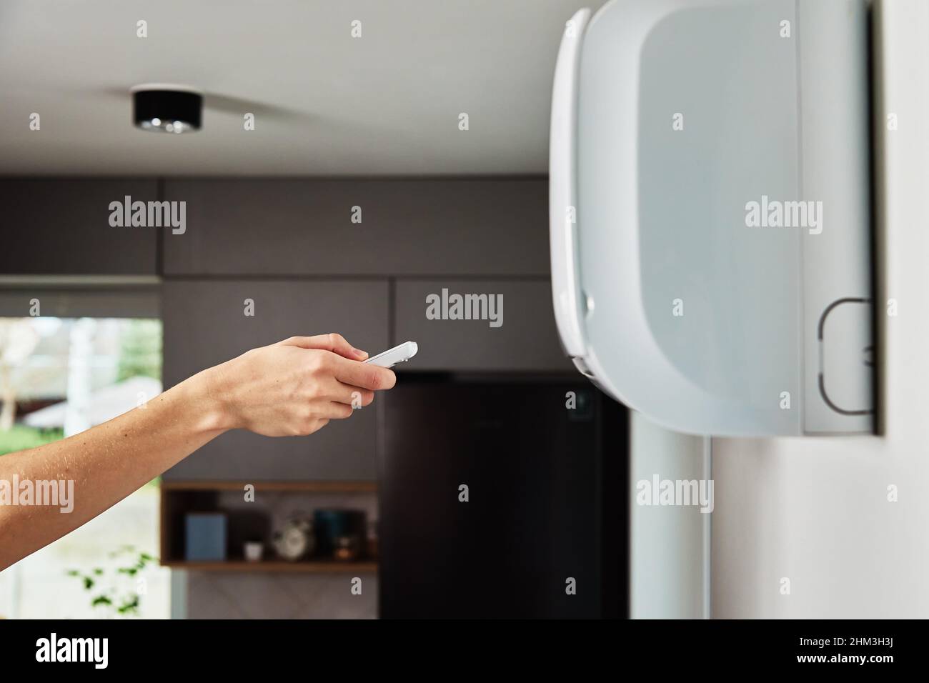 Hand adjusting temperature on air conditioner with remote control