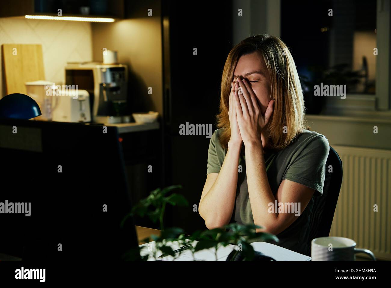 Tired woman works from home use computer at night, overwork burnout, freelancer works remote at home workplace Stock Photo