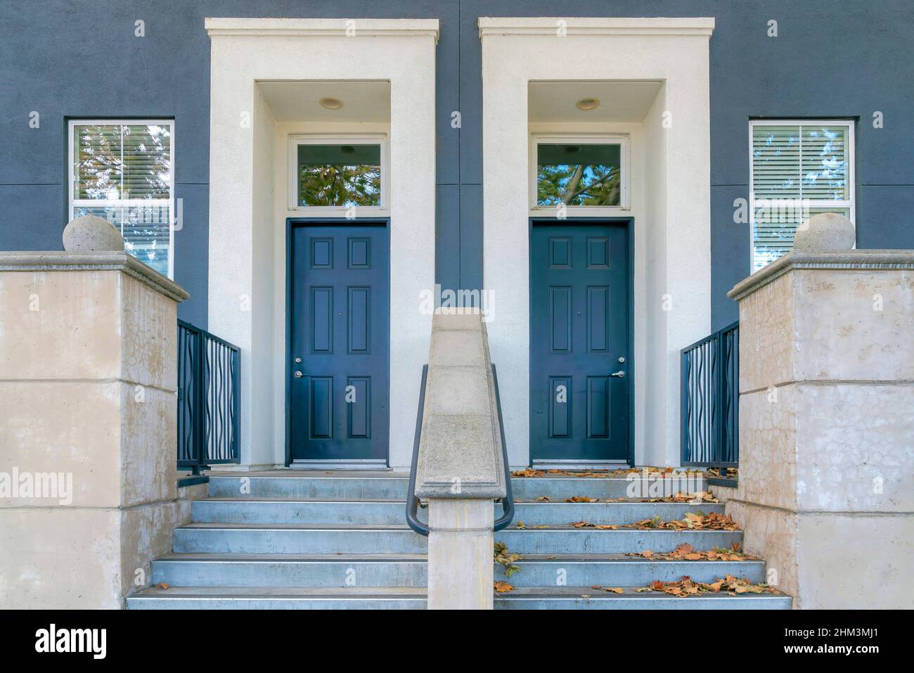 Two blue front doors with white doorframes and transom windows at San