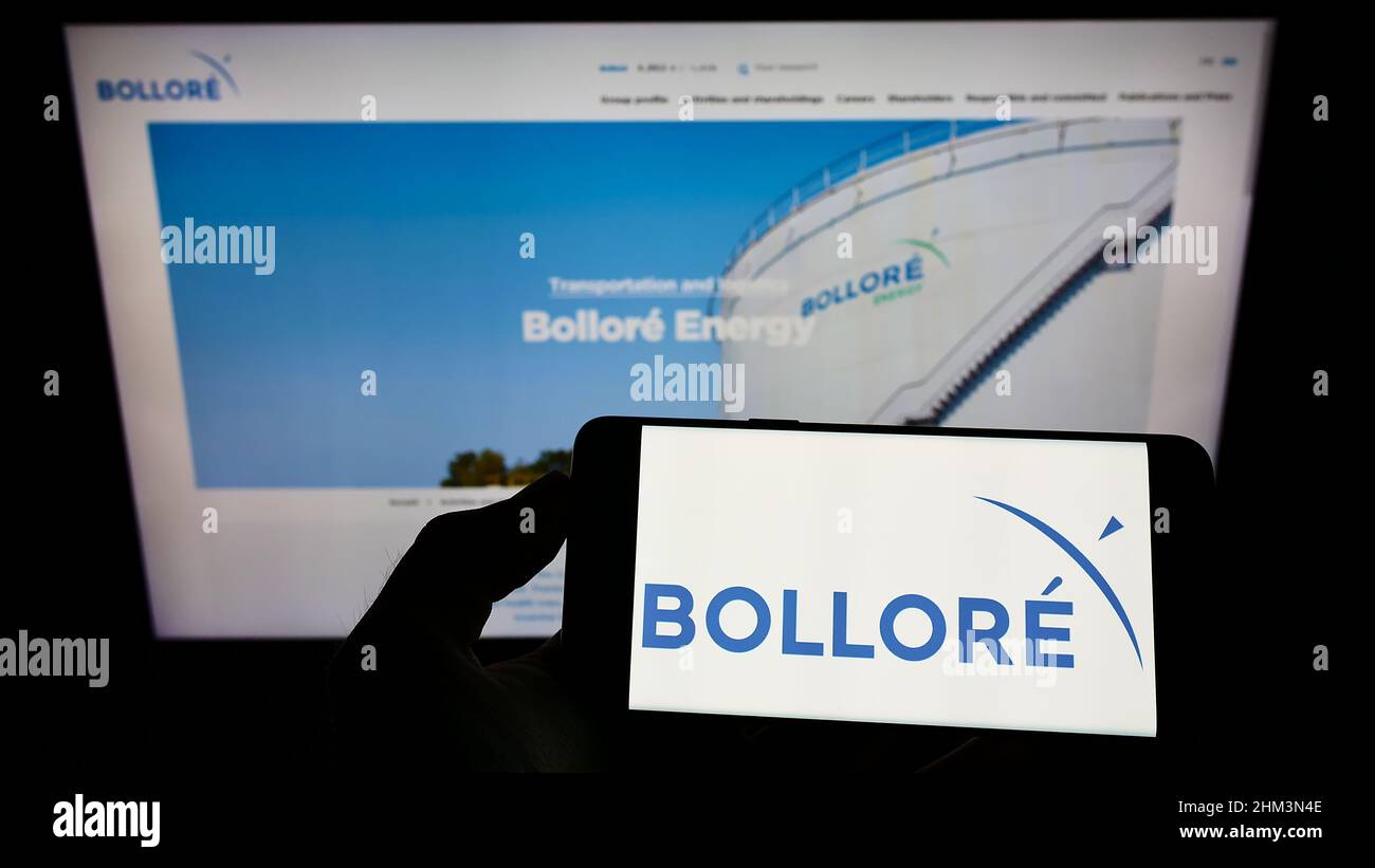 Person holding cellphone with logo of French conglomerate company Bollore SE on screen in front of business webpage. Focus on phone display. Stock Photo