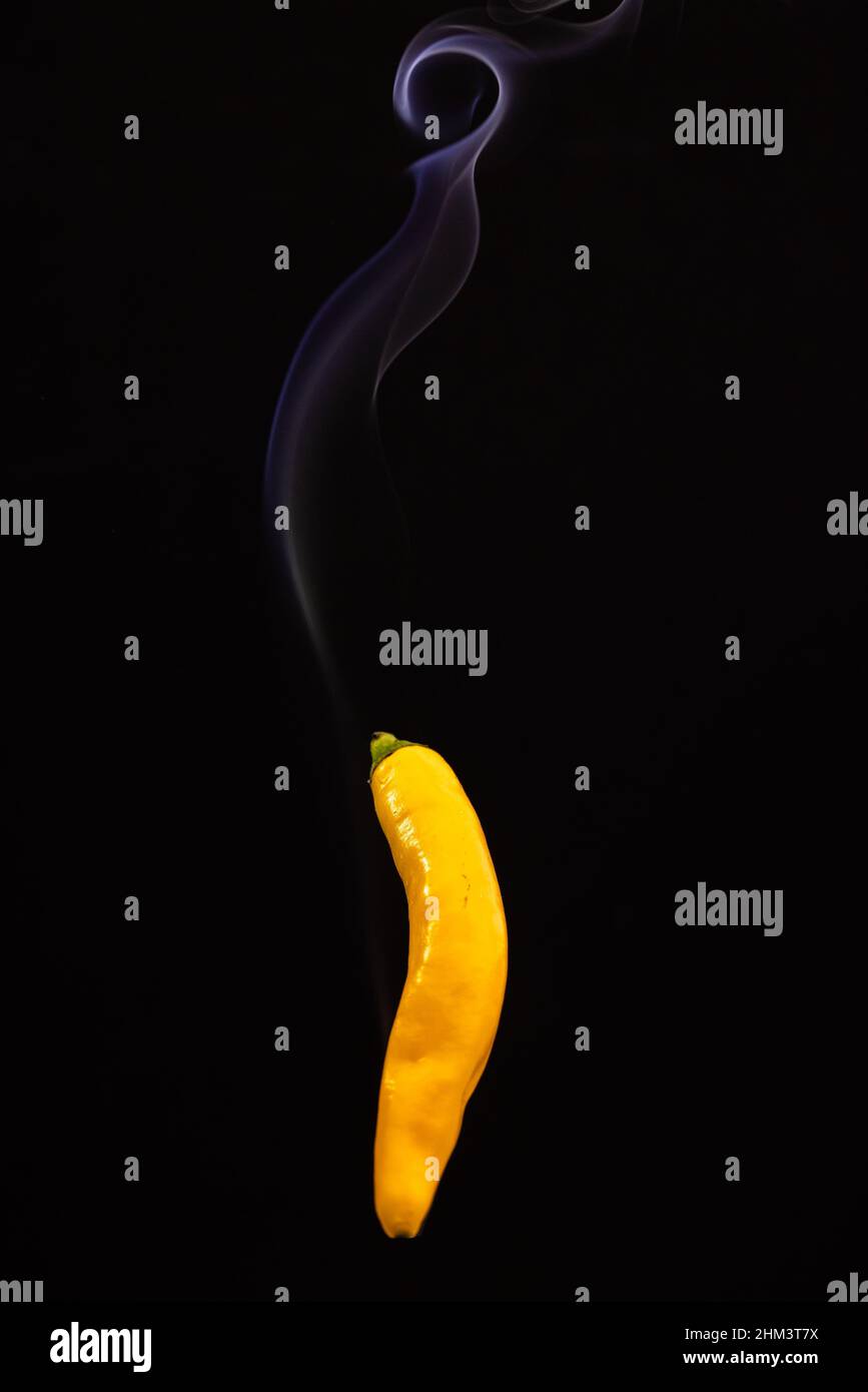 Yellow hot Mexican chili peppers against a black background with smoke coming from it, depicting it to be smoking hot. High quality photo Stock Photo