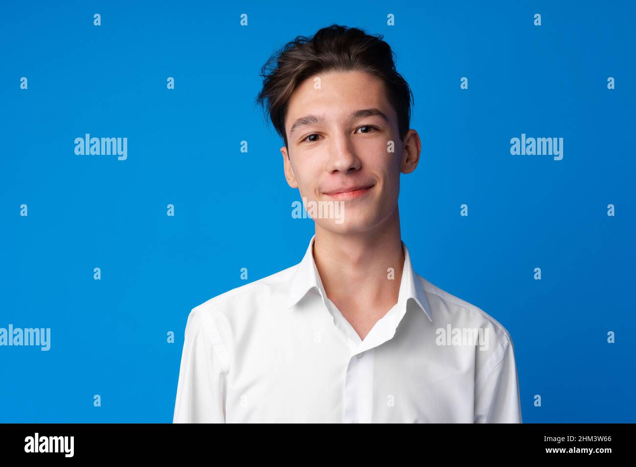 Portrait of a smiling teen boy against blue background Stock Photo - Alamy