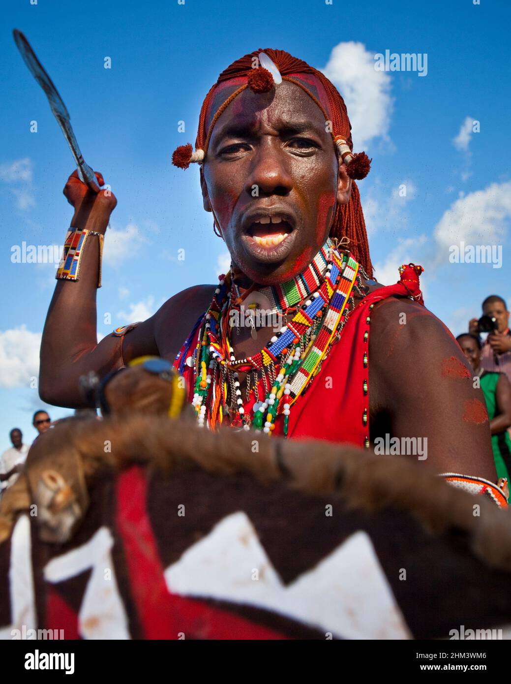 Maasai warrior from the Kenyan contingent brandishing a spear in a street performance at the Seychelles Carnival. Stock Photo