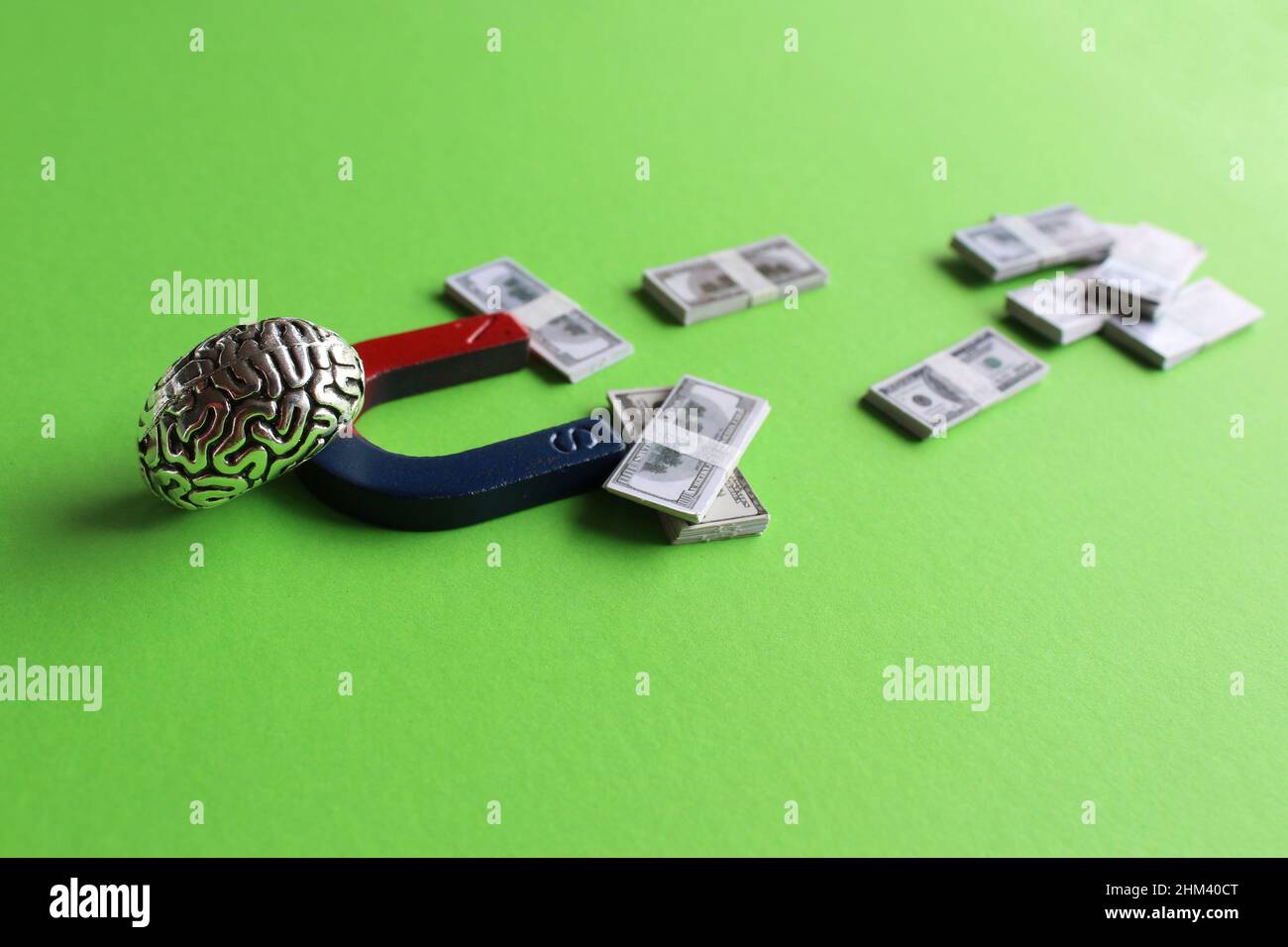 Business mindset, capitalism concept. Brain and magnet attract money on green background Stock Photo