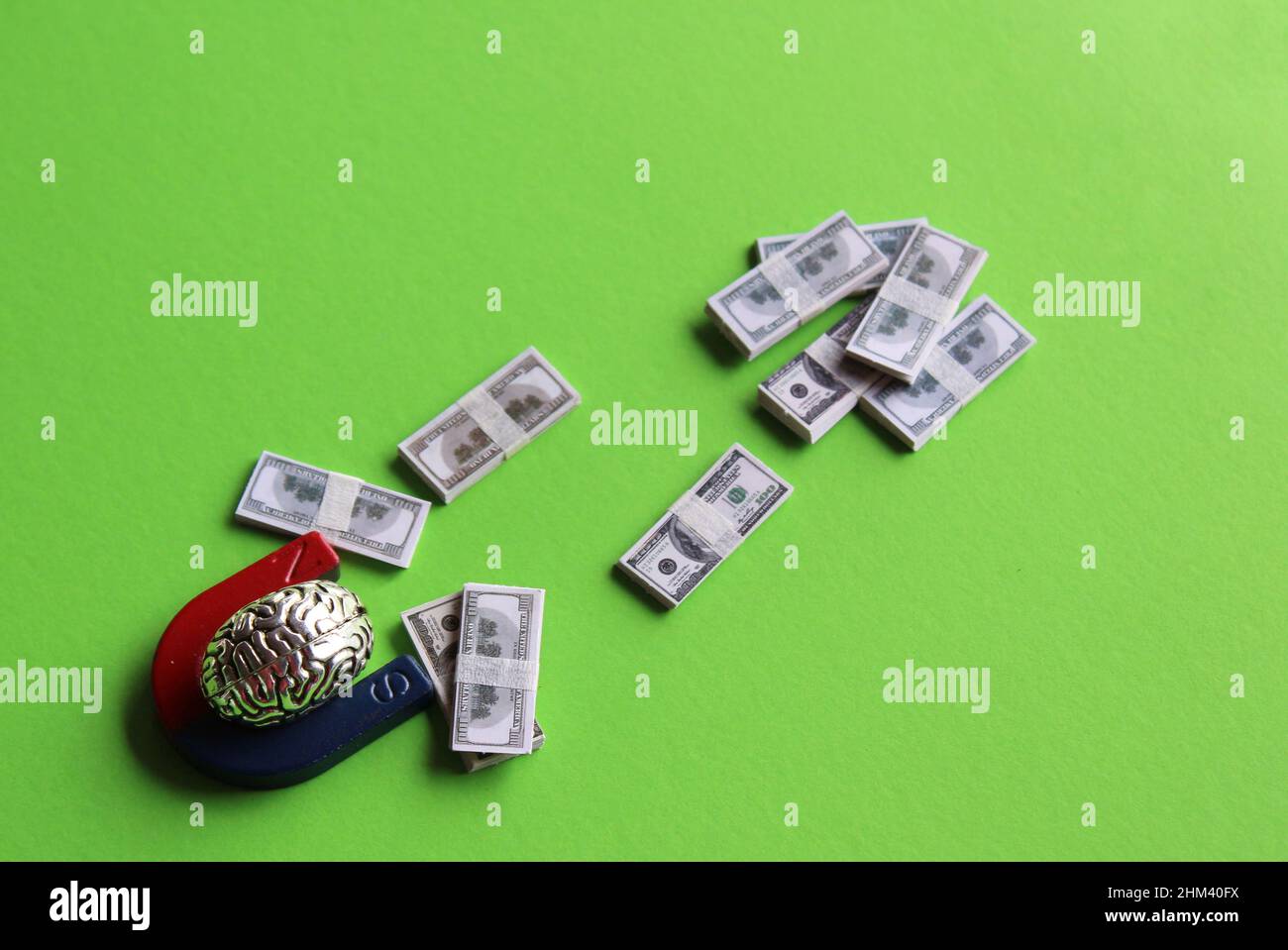 Business mindset, capitalism concept. Brain and magnet attract money on green background Stock Photo