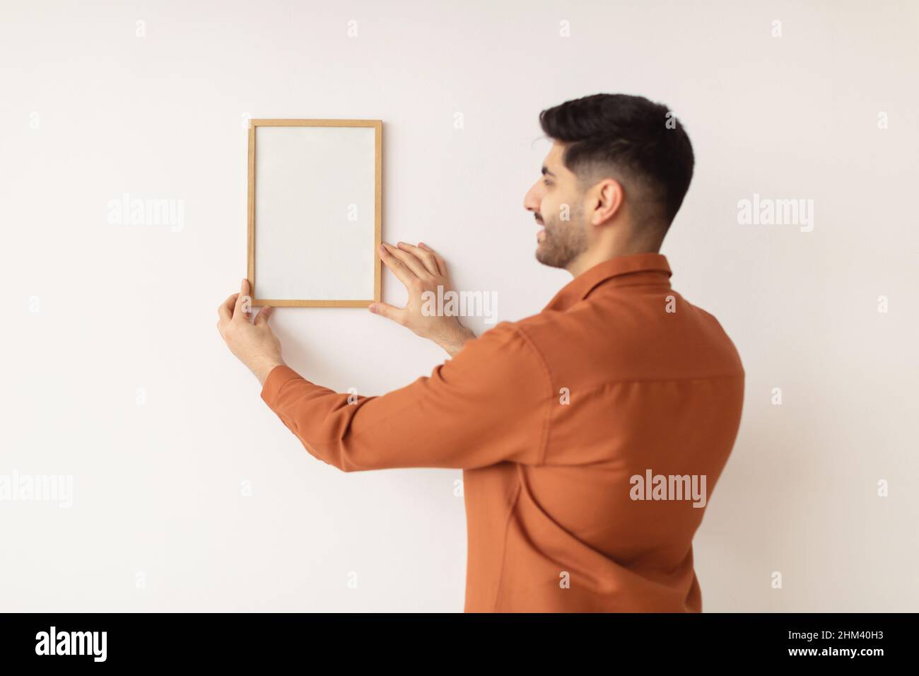 Young man hanging picture frame on the wall Stock Photo Alamy