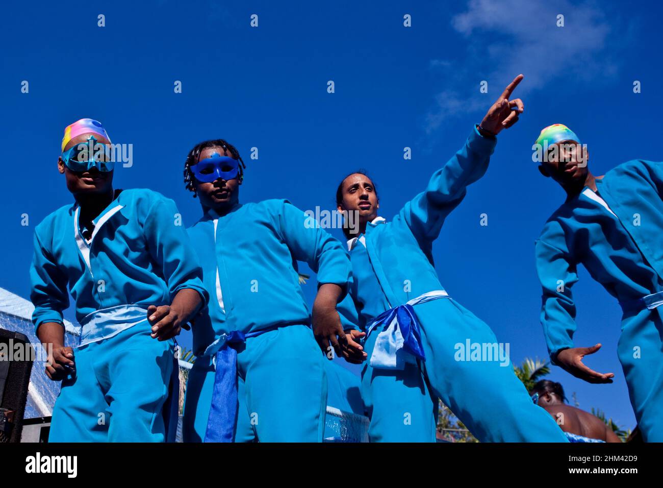 Four young men in matching blue suits celebrate carnival in the Seychelles. Stock Photo