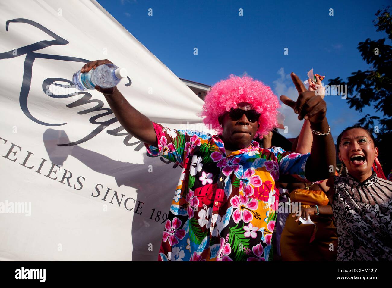 Man in pink afro wig dancing in the street during carnival in the Seychelles. Stock Photo