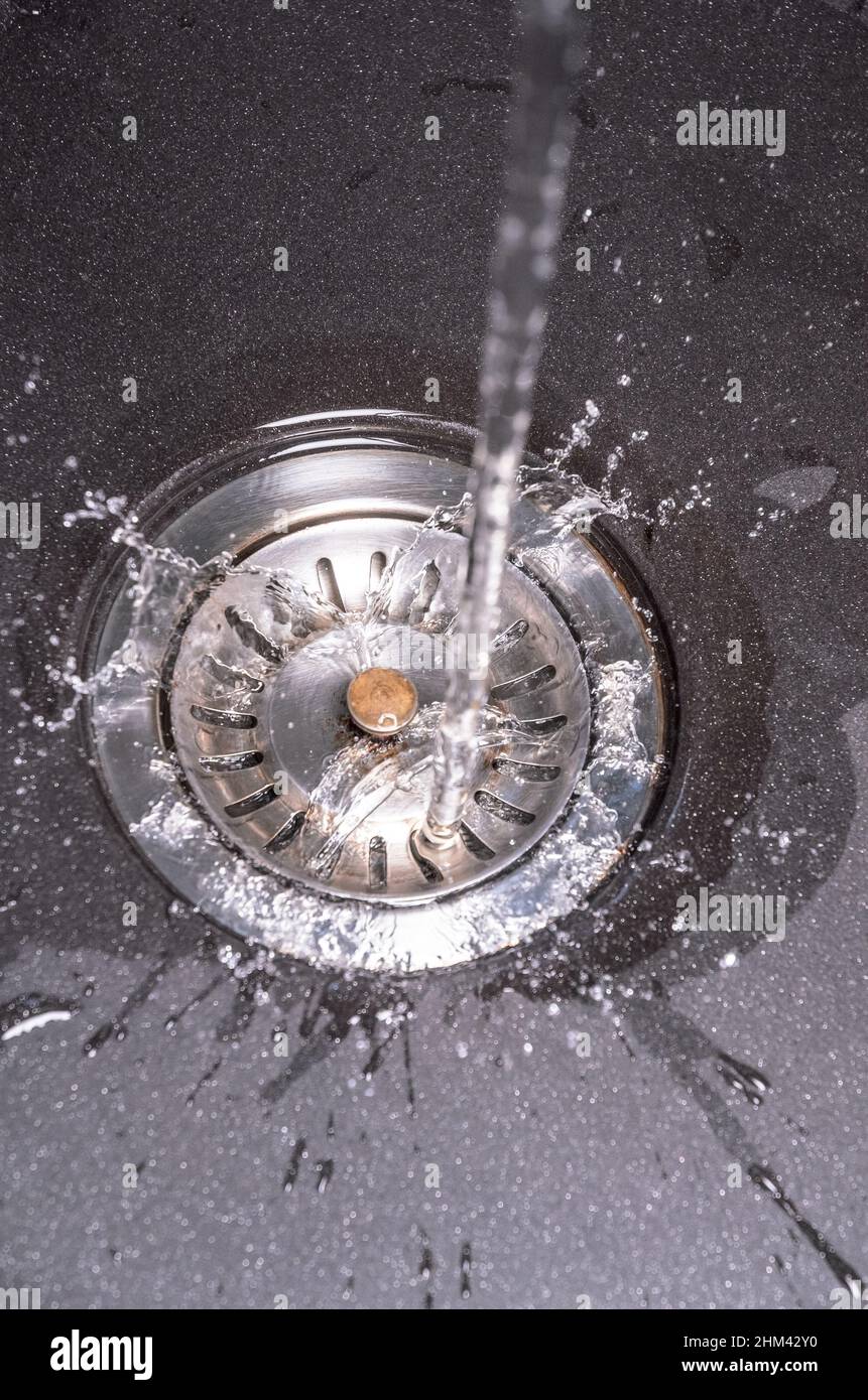 Modern stainless kitchen sink with water tap running, top view from