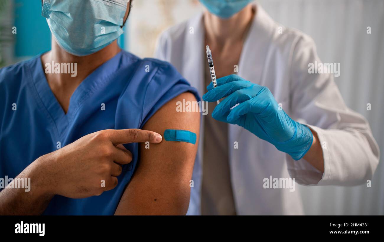 Close-up of unrecognizable doctor showing bandage on his arm after vaccince. Stock Photo
