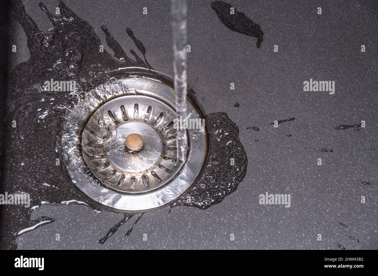 Modern stainless kitchen sink with water tap running, top view from