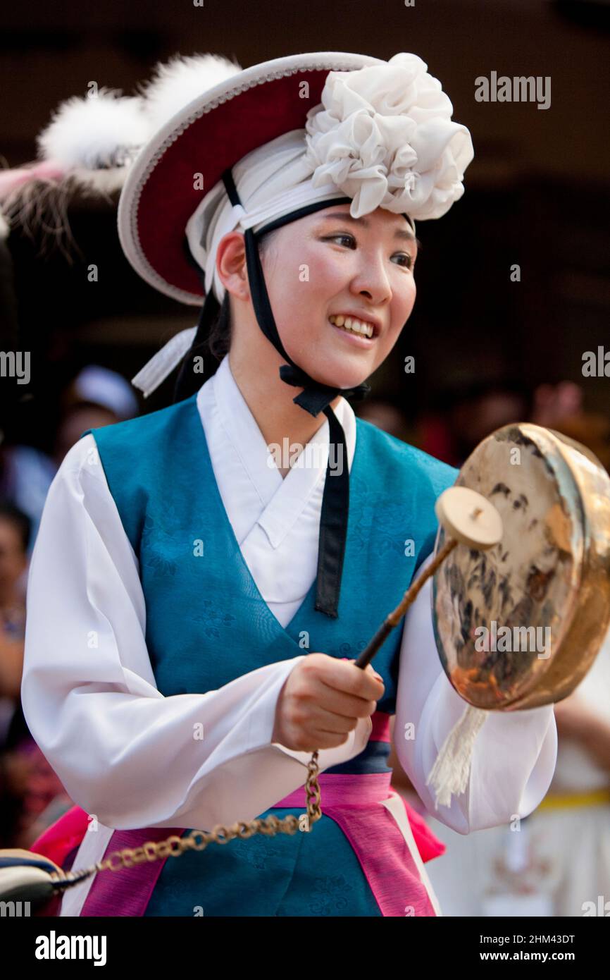 Korean performer in traditional dress bangs a drum in the street during Seychelles international carnival. Stock Photo