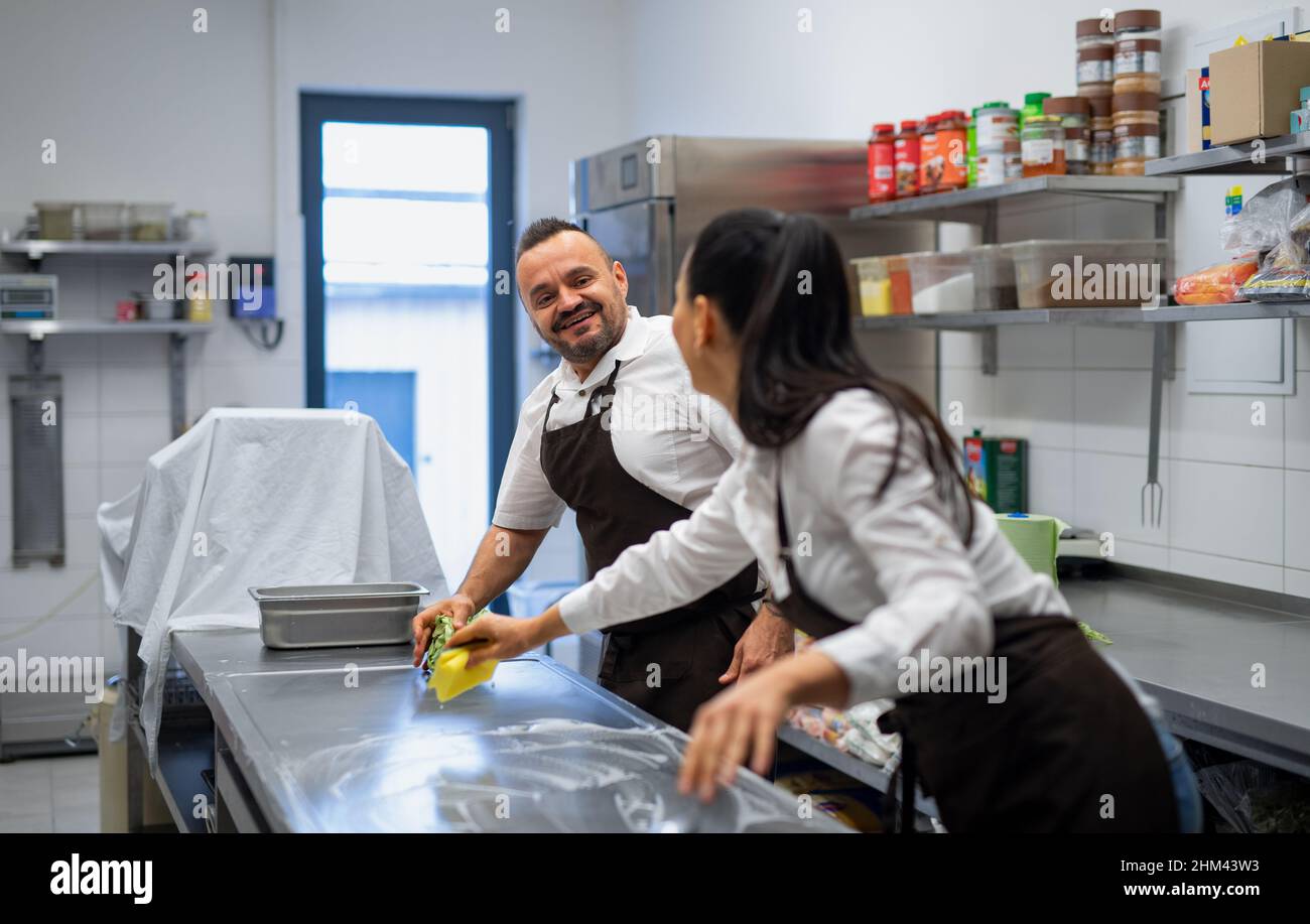 Chef and cook cleaning the workspace after doing dishes indoors in