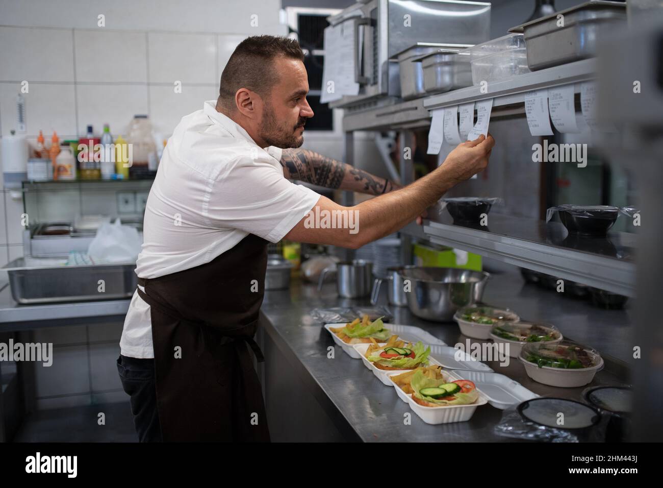 Chef taking order slip in commercial kitchen Stock Photo Alamy