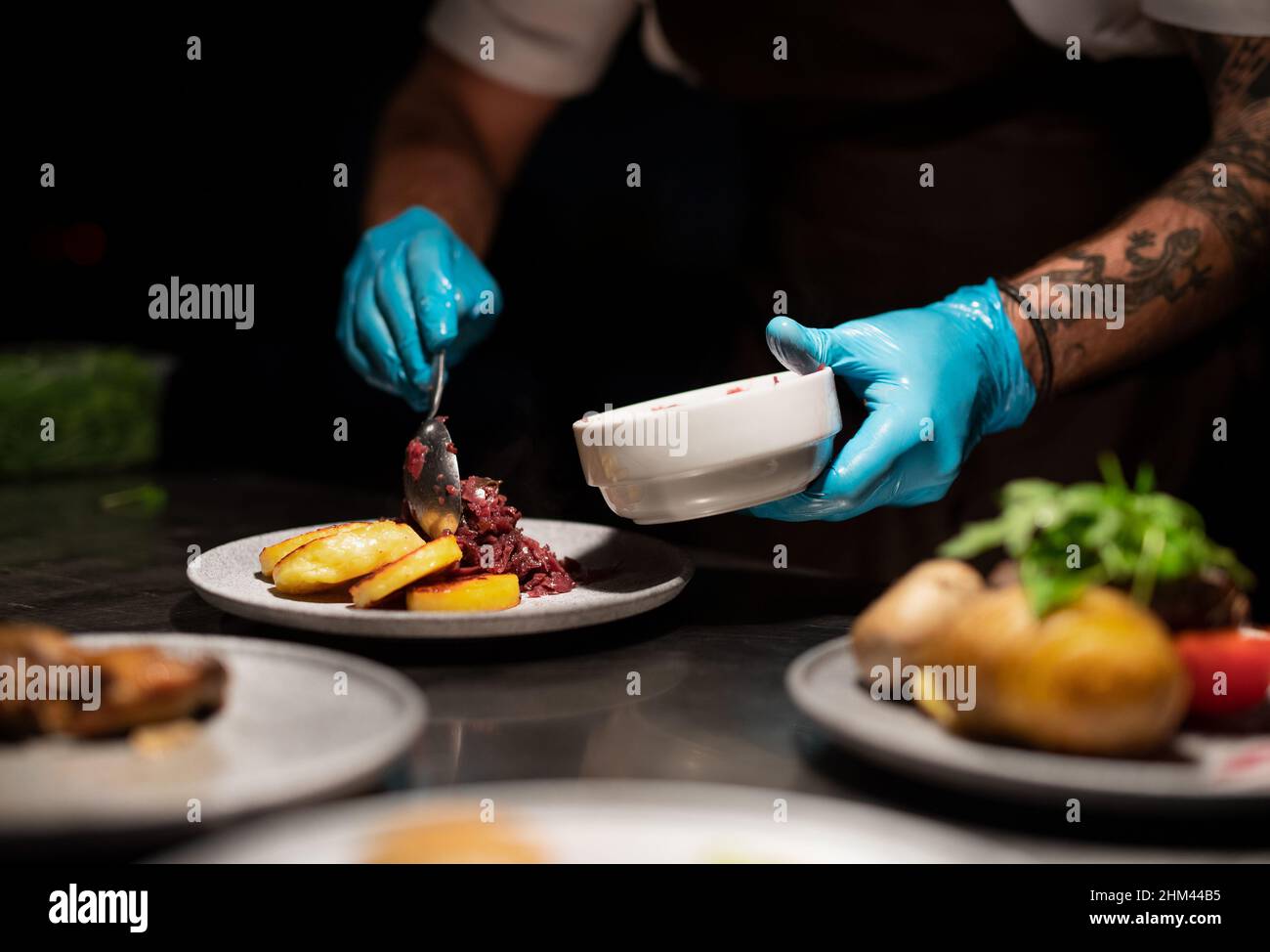 Chef's hands in gloves serving and decorating meal in restaurant