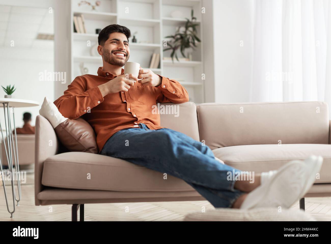 Man having rest at home on the couch, drinking coffee Stock Photo
