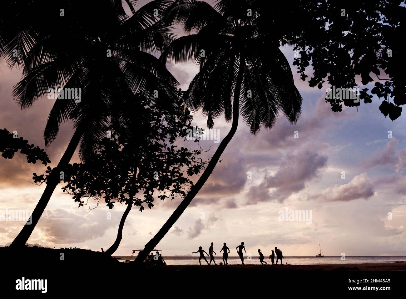 Silhouettes on Beau Vallon Beach playing football at sunset on Mahe Island, Seychelles. Stock Photo