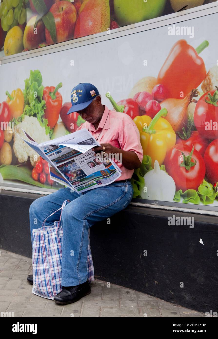 Seychellois reading the newspaper at a market in Victoria, Seychelles. Stock Photo