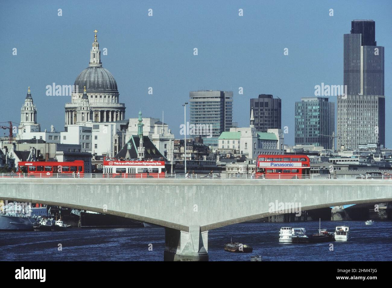 Red buses on Waterloo bridge with the city skyline and St Paul's Cathedral behind. London, England. Circa 1980's Stock Photo