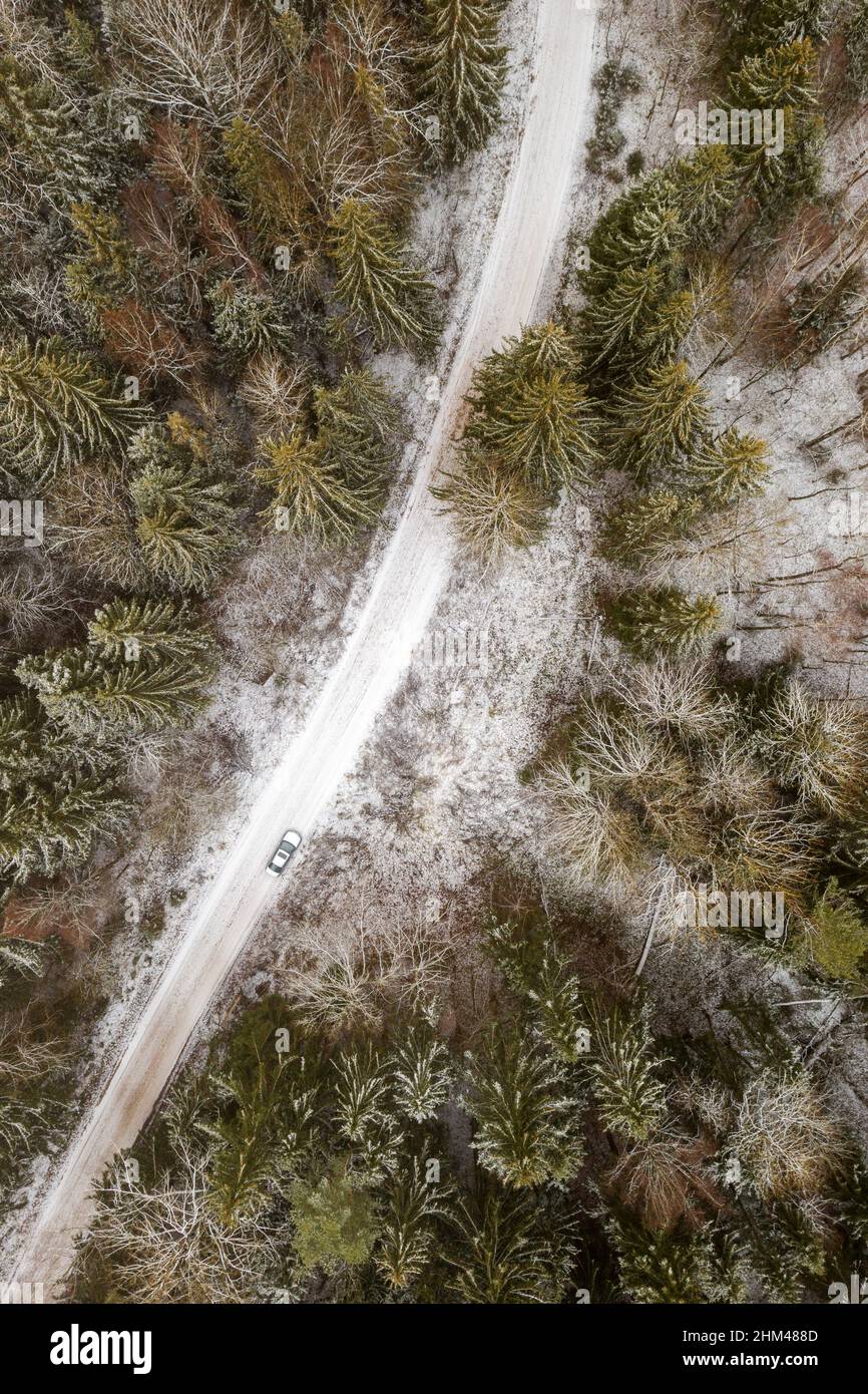 Car on rural road in winter with snow covered trees aerial view Stock Photo